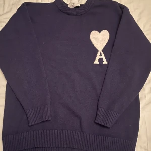 Mörkblå stickad tröja från Ami - Snygg mörkblå stickad tröja från AMI. Perfekt för dig som gillar stilrena detaljer och vill ha något som sticker ut.