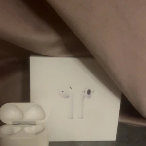 AirPods Pro - Säljer ett par Apple AirPods Pro med originalförpackning och laddningsetui. Hörlurarna är i fint skick, fungerar utmärkt och har aktiv brusreducering. Laddningsetuiets LED-lampa lyser grönt, vilket indikerar laddning. Inga synliga repor eller skador.