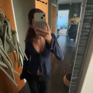 Mörkblå omlottopp från Gina Tricot - Supersnygg mörkblå topp från Gina Tricot, ny med prislapp, tröjan är lång ärmad och har en djup v-ringning. Toppen har knyt framtill.