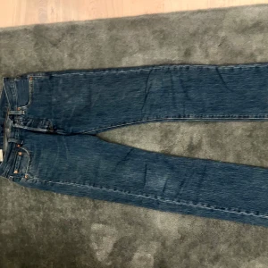 Levi's 501 blå jeans W28 L32 - Klassiska Levi's 501 jeans i blå denim med raka ben och normal passform. Byxorna har fem fickor, knappgylf och den ikoniska läderpatchen bak. Säljer dessa du jag har vuxit ut dem. Byxorna är mycket bra skötta och bra kvalitet. Om du har några funderingar tveka ej att fråga. Pris kan diskuteras vid snabbaffär