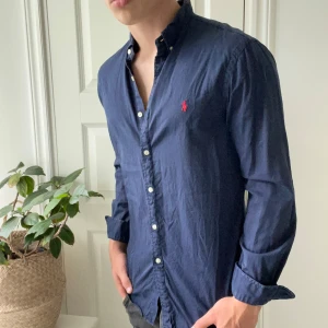 Ralph Lauren skjorta M slim fit mörkblå - Ralph Lauren skjorta M slim fit mörkblå, inga defekter, men använd. Modellen är 180,75 kg och bär M. 