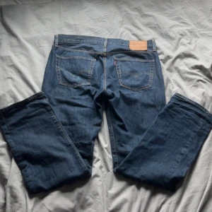 Levi's 501 blå jeans - Säljer ett par klassiska Levi's 501 Premium jeans i blå denim. Snygga kontrastsömmar och ikonisk läderpatch bak i midjan. Perfekta för en avslappnad look.