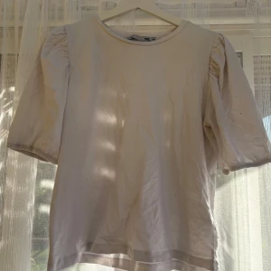 Vit puffärmad topp från 157 - Säljer en stilren vit topp från 157 med puffiga korta ärmar och rund halsringning. Toppen är gjord i mjuk bomull och har en enkel, clean look som passar perfekt till jeans eller kjol. Superskön och lätt att matcha med andra plagg.