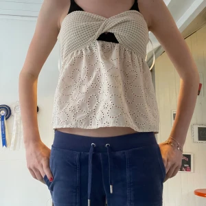 Beige broderad linnetopp med virkad byst - Supersöt beige linnetopp med virkad twistad byst och breda axelband. Nedre delen är i bomull med broderade blommor och hålmönster. Väldigt fin och bra att använda vardagligt eller när man vill vara extra fin. Aldrig använd. Sitter bra och åker inte av.