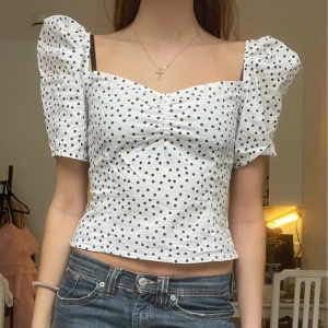 Vit prickig croppad blus med puffärm - Supersöt vit blus med svarta prickar och puffiga korta ärmar. Superfin att ha till vardagen men även till festligheter🩷