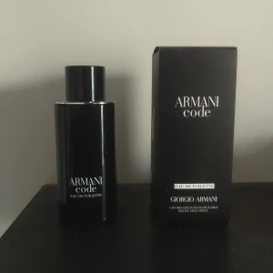 Armani Code Eau de Toilette 120/125ml - Säljer en stilren och elegant parfym, Armani Code Eau de Toilette från Giorgio Armani. Flaskan är svart med silverdetaljer och har en modern, cylindrisk form. Kommer i originalkartong som också är svart med vit text. Perfekt för dig som gillar exklusiva dofter.