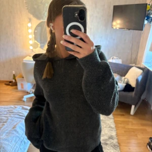 Mörkgrå stickad hoodie från AWARE XS - Mysig mörkgrå stickad hoodie från AWARE i storlek XS. Tröjan har långa ärmar, ribbade muddar och en skön huva. Perfekt för kyliga dagar när du vill vara både bekväm och snygg. Hoodien är stor för sin storlek skulle säga S/M. Aldrig använd mer än en gång hemma.