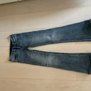 Blå jeans från Cheap Monday, bootcut - Säljer ett par blå bootcut jeans från Monday med klassisk femficksdesign och orange detalj i midjan. Jeansen har snygga slitningar framtill och är tillverkade av bomull, polyester och elastan för skön stretch. Perfekt passform och cool tvätt.