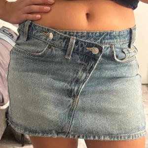 Blå jeanskjol  - Säljer en snygg jeanskjol med cool  knäppning framtill. Storlek M och är midwaist. 