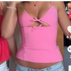 Rosa korsettopp med rosetter - Supersöt rosa korsettopp med smala axelband och två dekorativa rosetter framtill. Toppen har en snygg cut-out detalj under bysten och dragkedja i ryggen. Perfekt för dig som vill sticka ut med en feminin och trendig look. Inte mina bilder men skriv om du vill ha fler bilder på tröjan.  