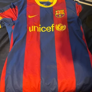 FC Barcelona Nike fotbollströja XL - Säljer en klassisk FC Barcelona fotbollströja från Nike i storlek XL. Tröjan har breda röda och blå ränder, gul krage och detaljer samt klubbmärke och Nike-logga på bröstet. Tillverkad i Dri-FIT material som andas, perfekt för match eller träning. riktig autentisk tröja från Barcelona matchen mot Manchester United 2010.