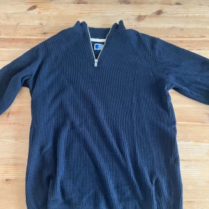 Mörkblå stickad tröja Jack & Jones - Mörkblå stickad tröja från Jack & Jones med ribbad struktur och half zip-dragkedja vid halsen. Långärmad modell som är perfekt för kyligare dagar. Enkel och stilren design som funkar till det mesta. Ingen fläck eller hål