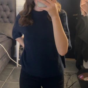 Mörkblå stickad tröja med kort ärm - Säljer en enkel och snygg mörkblå stickad tröja med rund hals och korta ärmar. Tröjan har en loose passform och är perfekt för dig som gillar en chill och stilren look. Passar bra till både jeans och kjol. Sällan använd så den är i jättebra skick, stl s💞