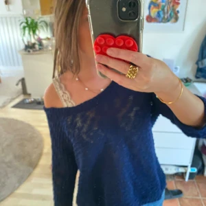 Mörkblå stickad offshoulder-tröja - Säljer en mörkblå stickad tröja med offshoulder-modell. Tröjan har en lös passform och långa ärmar, perfekt för dig som gillar en avslappnad och trendig stil. Materialet är stickat och känns mjukt mot huden. Snygg att bära över ett linne eller spets-bh.