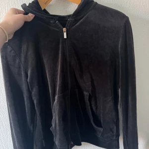 Svart velourhoodie från Gina Tricot - Mjuk och skön svart hoodie i velour från Gina Tricot. Tröjan har dragkedja framtill, huva och två fickor. Perfekt för en chill look och passar till allt. Långärmad och i klassisk passform.