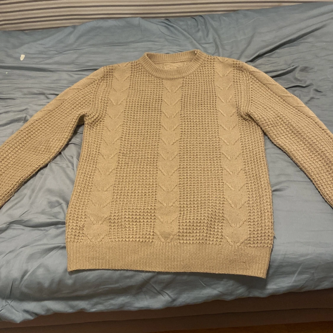 Beige stickad tröja med kabelmönster