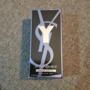 Yves Saint Laurent Y Eau de Parfum 100ml - Y Eau de Parfum från Yves Saint Laurent, 100 ml. Flaskan är stilren och rektangulär med svart och transparent glas, samt en metallisk etikett och grått lock med struktur. Doften är modern och maskulin, perfekt för dig som gillar exklusiva parfymer.