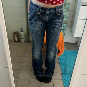 Blå bootcut jeans från Fornarina - Säljer dessa låtmidjade vintage jeans från Fornarina som tyvärr är för långa för mig💔🥀 Skitsnygg vit ”wash” med stora fickor fram och bak, orangea sömmar och knappar. 
