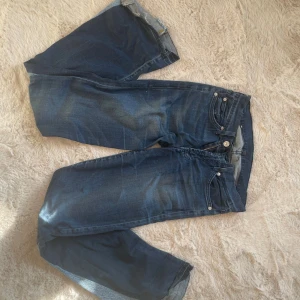 Mörkblå bootcut jeans  - Snygga mörkblå jeans  med klassisk femficksmodell och bootcut passform. Jeansen har låg midja, diskreta slitningar och silverfärgade detaljer. Perfekta för dig som gillar en tidlös och avslappnad look.