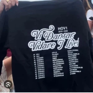 Svart Hov1 tourtröja Vi Dansar Vidare - Svart långärmad tröja från Hov1 med stor vit text på ryggen: 'Vi Dansar Vidare I Livet' och turnédatum. Perfekt för dig som älskar svensk musik och vill ha en snygg merch med coolt tryck. Storlek L men sitter som en storlek M