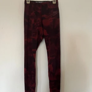 Nike leggings i vinröd camo XS - Snygga vinröda leggings från Nike i storlek XS med camo-mönster. Tight passform med elastisk midja och diskret Nike-logga framtill. Fint skick!