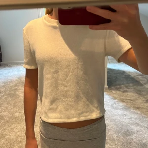Vit stickad t-shirt - Säljer en vit stickad t-shirt med korta ärmar och rund hals  och har en enkel, clean look utan mönster eller tryck. Perfekt för dig som gillar minimalistisk stil och vill ha en skön och lätt topp.