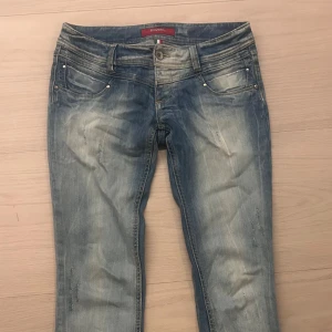 Lågmidjade ljusblå jeans från Tank  - Säljer ett par lågmidjade ljusblå jeans från Tank med slitna detaljer och klassisk femficksdesign. Jeansen har en snygg tvätt med ljusa partier och kontrastsömmar. Perfekt för dig som gillar en trendig look. Det har även blixtlås längst ner på byxorna. Köpta på en vintage butik inne i Malmö men har inte kommit till så stor användning ❤️ priset går att buda på!!