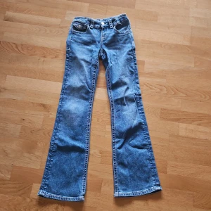 Blå bootcut jeans med broderade fickor från Gina Tricot. - Snygga blå jeans med bootcut passform och broderade detaljer på bakfickorna. Klassisk femficksmodell med knapp och dragkedja fram. Jeansen är tillverkade i jeansmaterial med stretch i midjan för extra komfort.