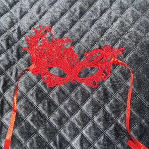 Röd mask - Röd mask i spets med detaljerade mönster och knytband. 