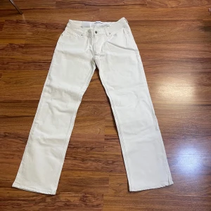 Vita jeansbyxor från Stay, rak modell - Snygga vita jeansbyxor från Stay i rak och klassisk modell. Byxorna har fem fickor, bälteshällor och knappstängning framtill. Materialet är mjukt och slitstarkt jeans, perfekt för dig som gillar stilrena och ljusa looks.