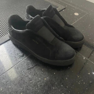 axel arigato herr skor - Snygga svarta sneakers från Armani med stilren design och rund tå. Skorna är tillverkade i mocka och har elastiska paneler istället för klassisk snörning, vilket ger en modern look. Platt sula och diskret logga på sidan. Perfekta för dig som gillar minimalistisk stil.