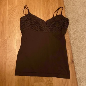 Brun spetslinnetopp Banana Republic - Brunt linne från Banana Republic i storlek XL (upplevs M) med tunna axelband och blommönstrad spets upptill. Toppen har en figurnära passform och är tillverkad i stretchigt material med spetsdetaljer över bysten. Inga defekter.