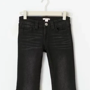 Svarta jeans med nitar på bakfickan - Snygga svarta jeans med klassisk femficksdesign och coola silverfärgade nitar som dekorerar bakfickan. Jeansen har en rak passform och är tillverkade i mjukt denim-material med lätt tvättad look framtill. Perfekt för dig som gillar detaljer och vill sticka ut,storleken är 158 men sitter som en s.