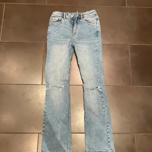 Blå jeans från LAB Industries, strl 158 - Snygga ljusblå jeans från LAB Industries i Flare och hål vid knäna. Jeansen är tillverkade i hållbar denim och har en normal passform.