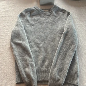 Grå stickad tröja från A Day's March - Mysig grå stickad tröja från A Day's March i storlek small. Tröjan har rund halsringning, ribbade muddar och är långärmad. Perfekt för lager-på-lager under kyliga dagar och har en klassisk, enkel look. Köpte den och har aldrig använt den