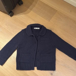 Mörkblå stickad kofta från Zara - Mysig mörkblå stickad kofta från Zara med klassisk krage, knappar framtill och två fickor. Koftan har tre kvarts ärmar finns ej längre☺️