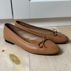 Beige ballerinaskor från Zara - Beiga ballerinaskor från Zara med rund tå och rosett framtill. Använda handfull av gånger, fortfarande i fint skick 