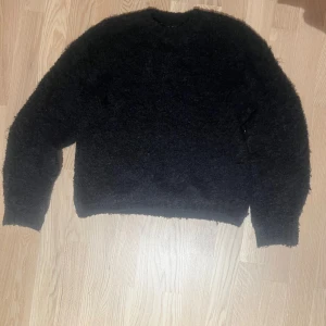 Svart stickad tröja - Svart stickad tröja med fluffig yta och rund hals.