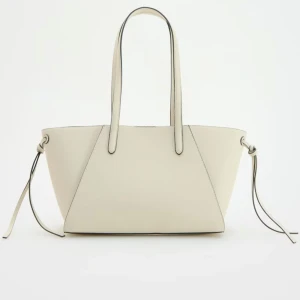 Beige shoppingväska med snörning - Stilren shoppingväska i beige med två långa handtag och coola snörningsdetaljer på sidorna. Väskan har en modern, kantig form och är tillverkad i syntetmaterial med lätt struktur. Perfekt för dig som vill ha en rymlig och trendig väska till vardags. köpt för 450kr, oanvänt 