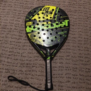 Padel rack - Säljer mitt Babolat Revenge Lite padelracket i fint skick. Lätt och smidigt racket med fokus på kontroll och spelkänsla. Snygg design i svart med neongula detaljer. Rund form och vikt runt 350–360 g gör det lättspelat och bekvämt. Tillverkat i glasfiber med EVA Soft Foam-kärna för mjuk och skön träff.