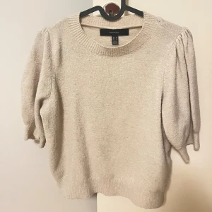Beige stickad tröja Vero Moda XS - Superfin beige stickad tröja från Vero Moda i storlek XS. Tröjan har puffiga trekvartsärmar och bred ribbad rund halsringning. Mjuk och skön kvalitet.