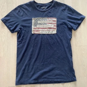 Mörkblå t-shirt Ralph Lauren M - Säljer denna snygga T-shirt från Ralph lauren i storlek M. Kolla bild 4/5 där det finns små hål, kan ses som defekter men på grund av tröjans design märker man inte av dem. Kom med bud eller vid frågor skriv bara!