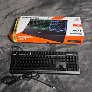 SteelSeries Apex 3 - SteelSeries Apex 3 gamingtangentbord i mycket fint skick, komplett med handledsstöd, originalkartong och manual. RGB-belysning, tysta tangenter och IP32-vattenskydd. Perfekt för PC, Mac, Xbox One och PS4. Inga synliga defekter eller slitage. Helt nytt!!!! Min pojkvän använder vanligtvis ett litet tangentbord, så det här var för stort för honom.