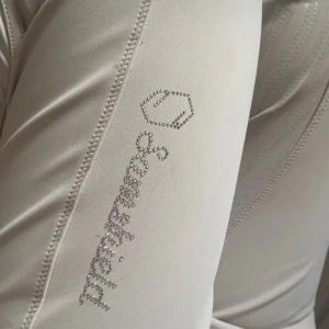 Beige ridbyxor Samshield strl 40 - Snygga beige ridbyxor från Samshield i väldigt bra skick, har väldigt skön passform och grepp i sadeln. Säljer då jag köpte dem av någon som lutade mig på storleken då jag sökte 36 men dessa är i 40. Så tar även byte om det skulle vara intressant