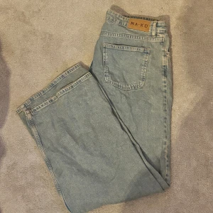 Wide jeans från NA-KD i ljusblå denim - Säljer ett par ljusblå jeans från NA-KD med klassisk femficksdesign och breda ben. Jeansen har normal midja och är tillverkade i mjuk denim. Perfekta för dig som gillar en avslappnad och trendig look.