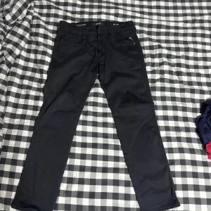 Replay Anbass svarta jeans - Svarta Replay Anbass jeans med klassisk femficksdesign och diskreta sömmar. Slimmad passform och stretchigt Hyperflex-material som ger grym komfort. Bara att skriva om ni vill ha mått!