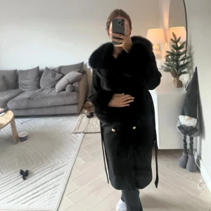 Pälskappa oanvänd nypris 4000 - Oanvänd. Ull. Äkta päls. Nypris 4000. Säljer en elegant svart kappa med lyxiga pälsdetaljer på krage och ärmslut. Perfekt för kalla vinterdagar och höstpromenader. Kappan har en klassisk design med knappar framtill och ett bälte i midjan för en snygg passform. 