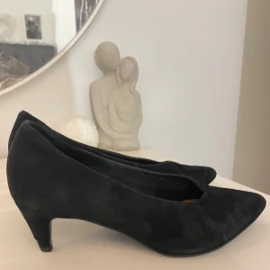 Svarta mockapumps med spetsig tå - Snygga svarta pumps från & Other Stories i mjuk mocka. Skorna har spetsig tå och låg klack ca 6 cm. Skorna är i storlek 36 men skulle säga att de är stora i storleken och skulle passa en 37a eftersom jag har 36 och dessa är för stora för mig 😊Bara att skriva om ni har frågor! Har slitning på klacken som ni kan se i sista bilden. 
