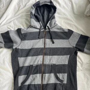 Grå randig hoodie  - Grå randig hoodie med text på insidan precis vid nacken. 