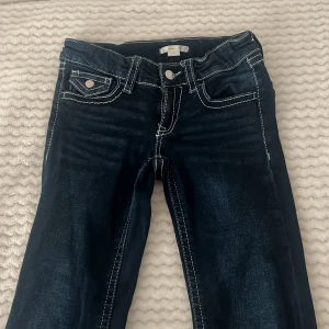 Mörkblå bootcut jeans Gina Tricot - Snygga mörkblå jeans från Gina Tricot med bootcut passform och kontrasterande vita sömmar. Jeansen har fickor med lock och knapp både fram och bak, samt klassisk knapp och dragkedja i midjan. Perfekt för dig som gillar en cool och tidlös jeanslook. Har använt dessa byxor ungefär 3 gånger. Ord pris:360kr.  Priset kan även diskuteras❣️